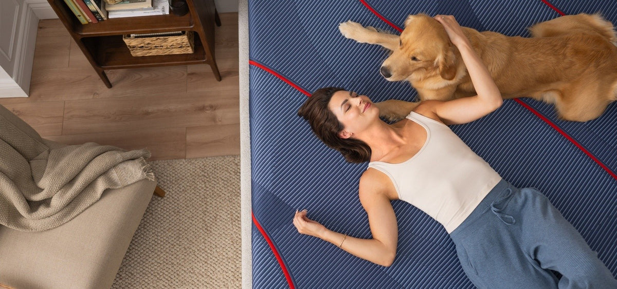 A woman and dog laying on a Posturepedic Elite Hybrid mattress