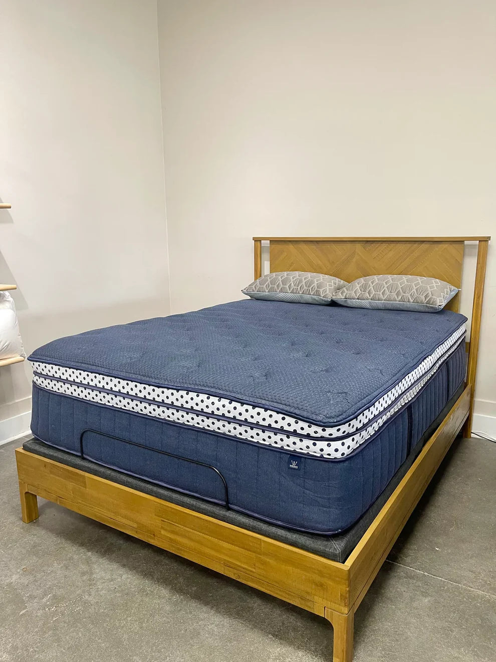 Winkbed Blue mattress on a wooden bed frame against a white wall.